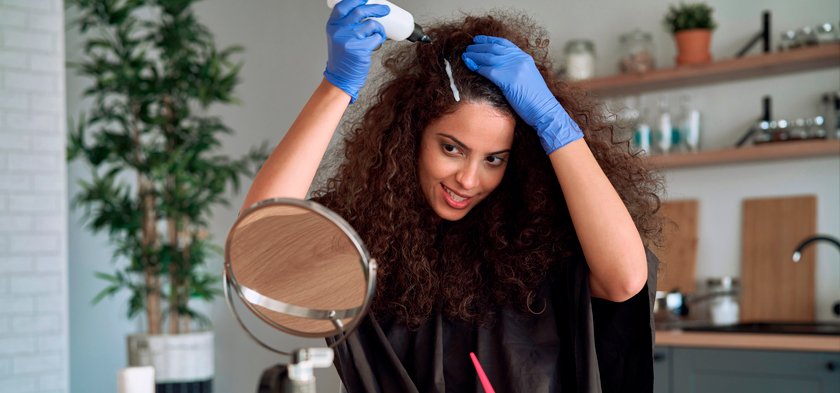 кудрявая брюнетка красит корни волос дома